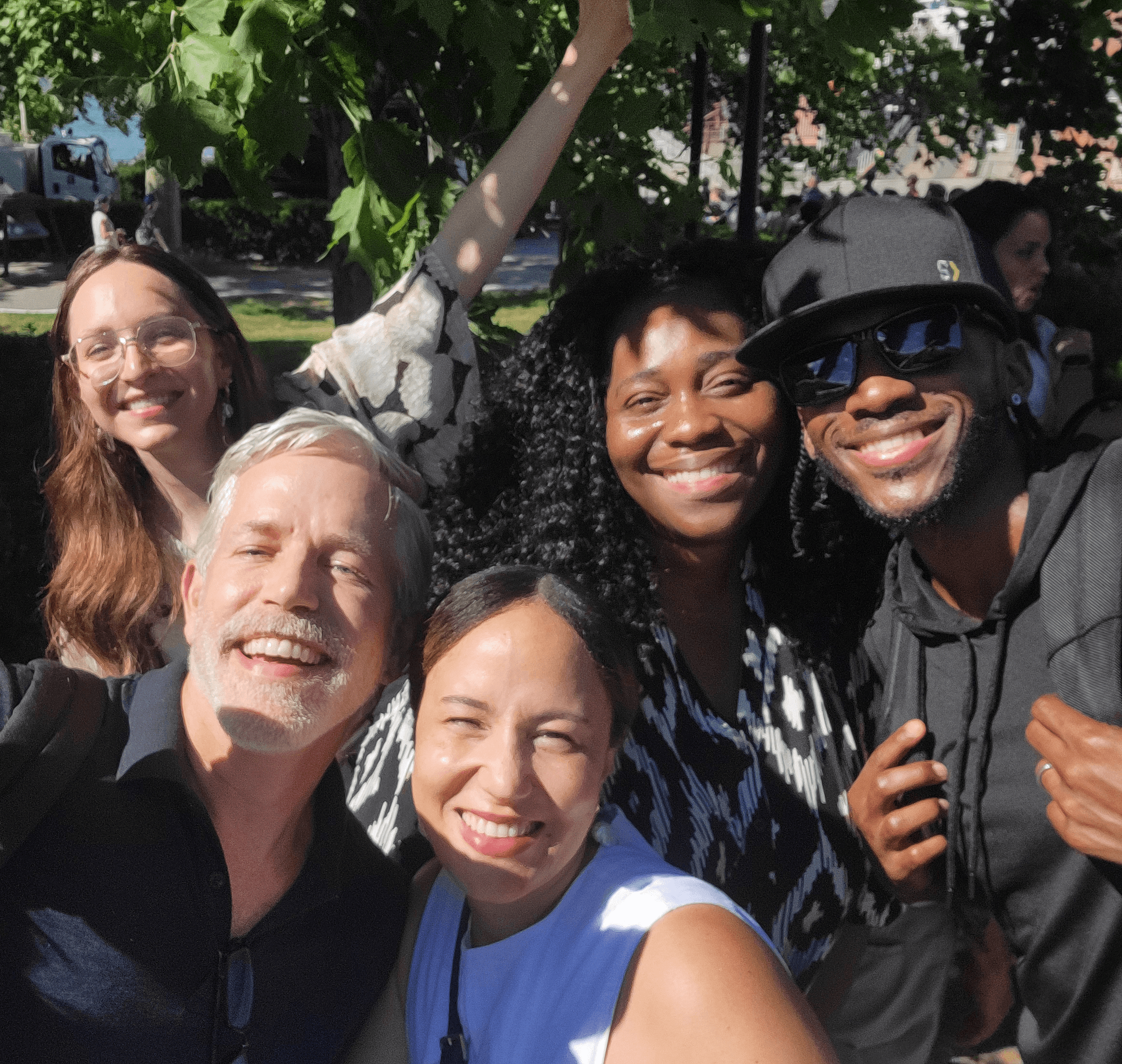 5 people huddled closely together for a photo in the park